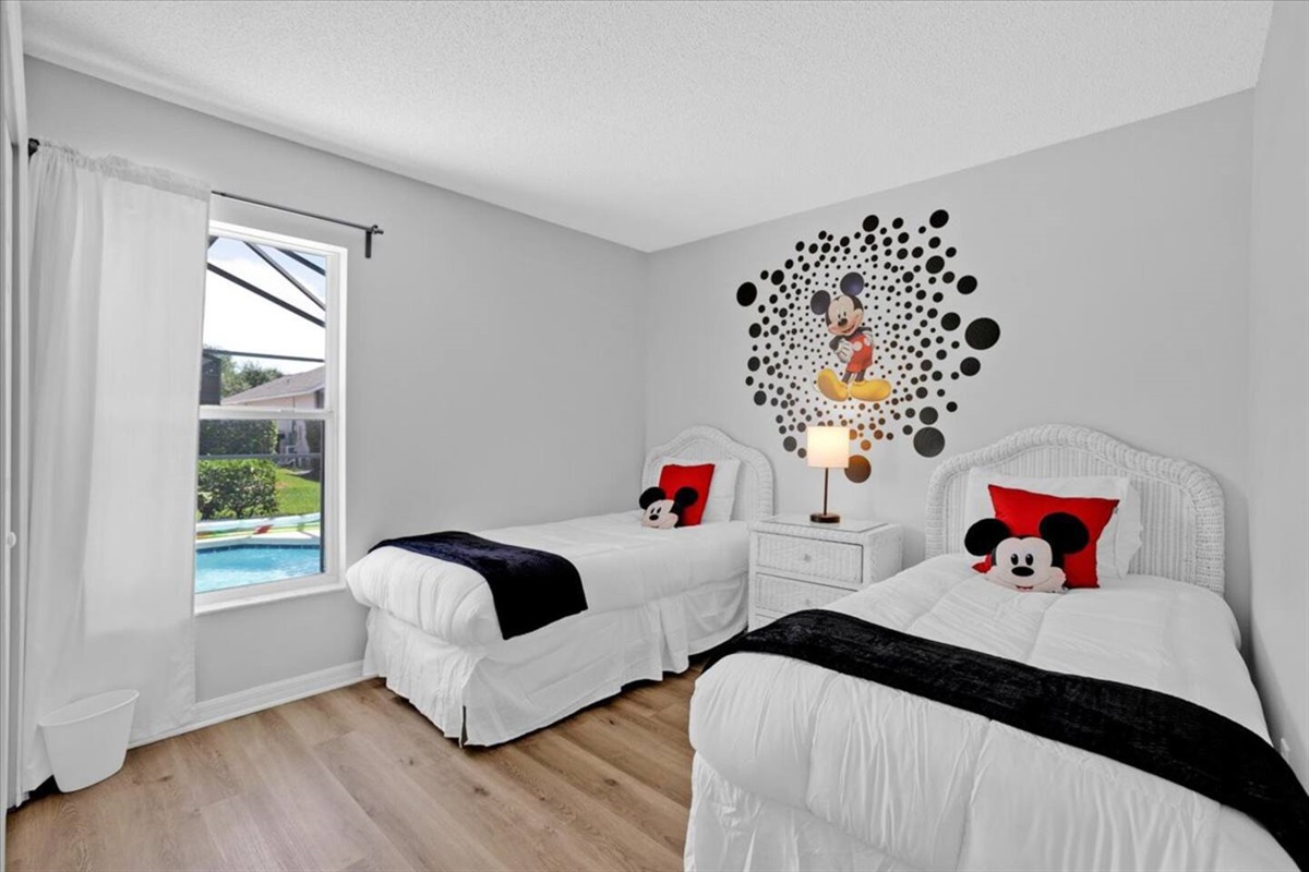 The second bedroom has two single beds, Mickey decor, and a window overseing the pool area.  