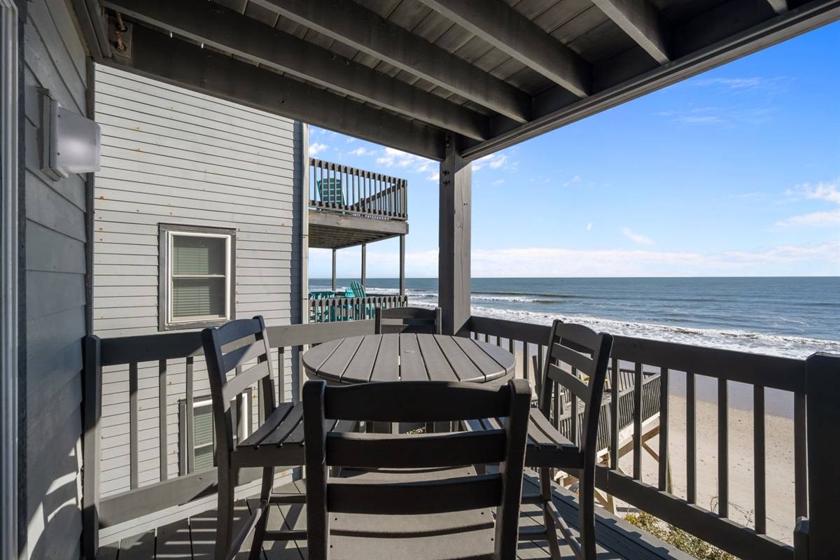 Covered oceanfront deck with a caf&eacute;-style table: perfect for morning coffee, sunset dinners, and lingering over the sound of the waves just below