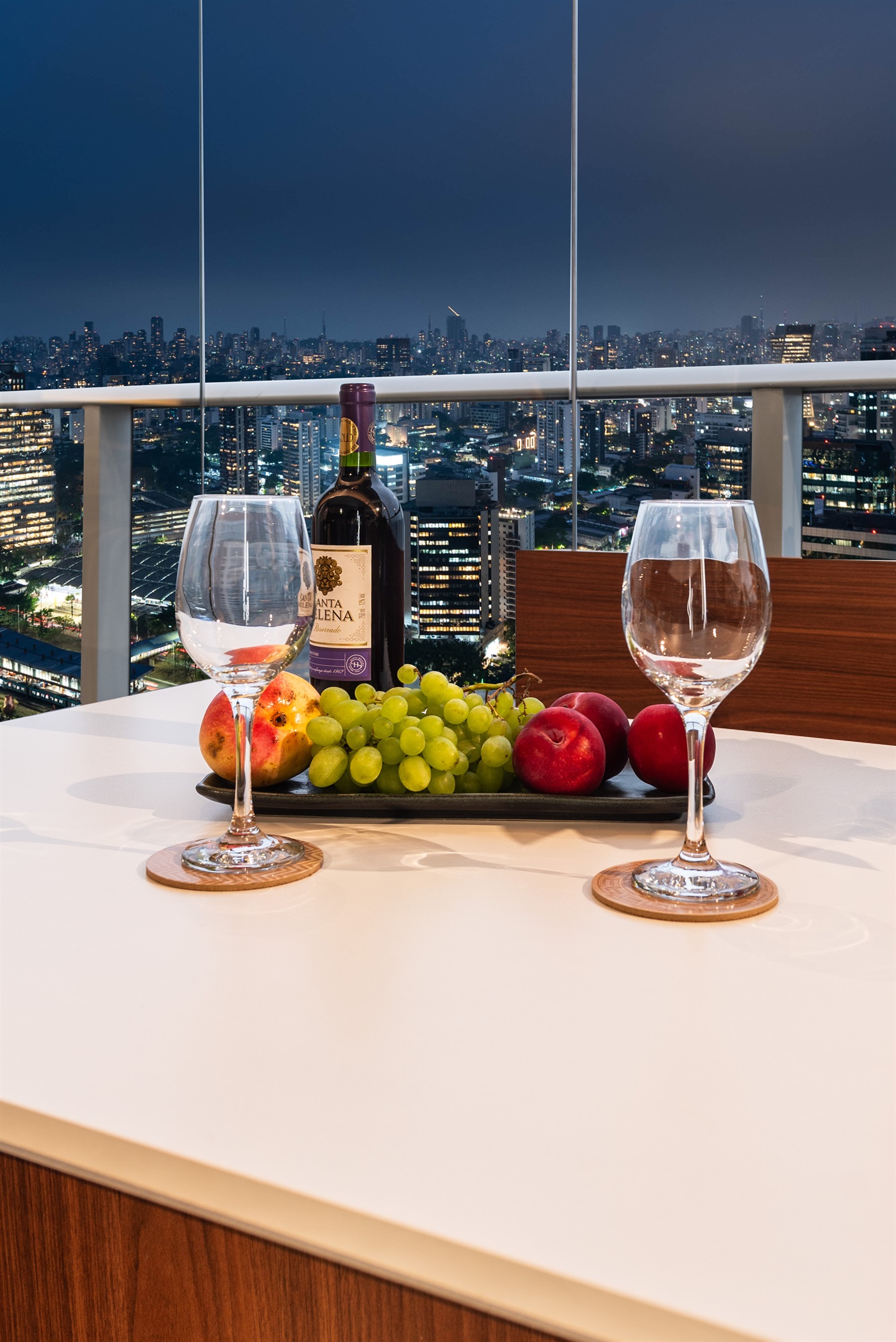 Detalhe lifestyle 🍷 Experiência única: vinho e frutas à mesa com a vista noturna da cidade. Ambiente sofisticado que combina conforto e elegância no River One.