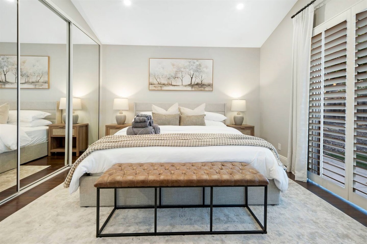 The primary bedroom features a cozy king bed with plush linens, nightstands with built-in charging stations for convenience, ensuring devices are always ready. Blackout curtains ensure a restful sleep by blocking out light for a peaceful atmosphere.