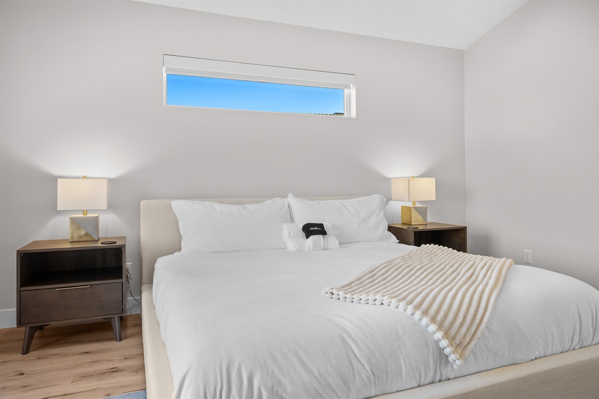 Retreat to the serene Primary Suite featuring a plush King bed and soft natural light streaming through clerestory windows.