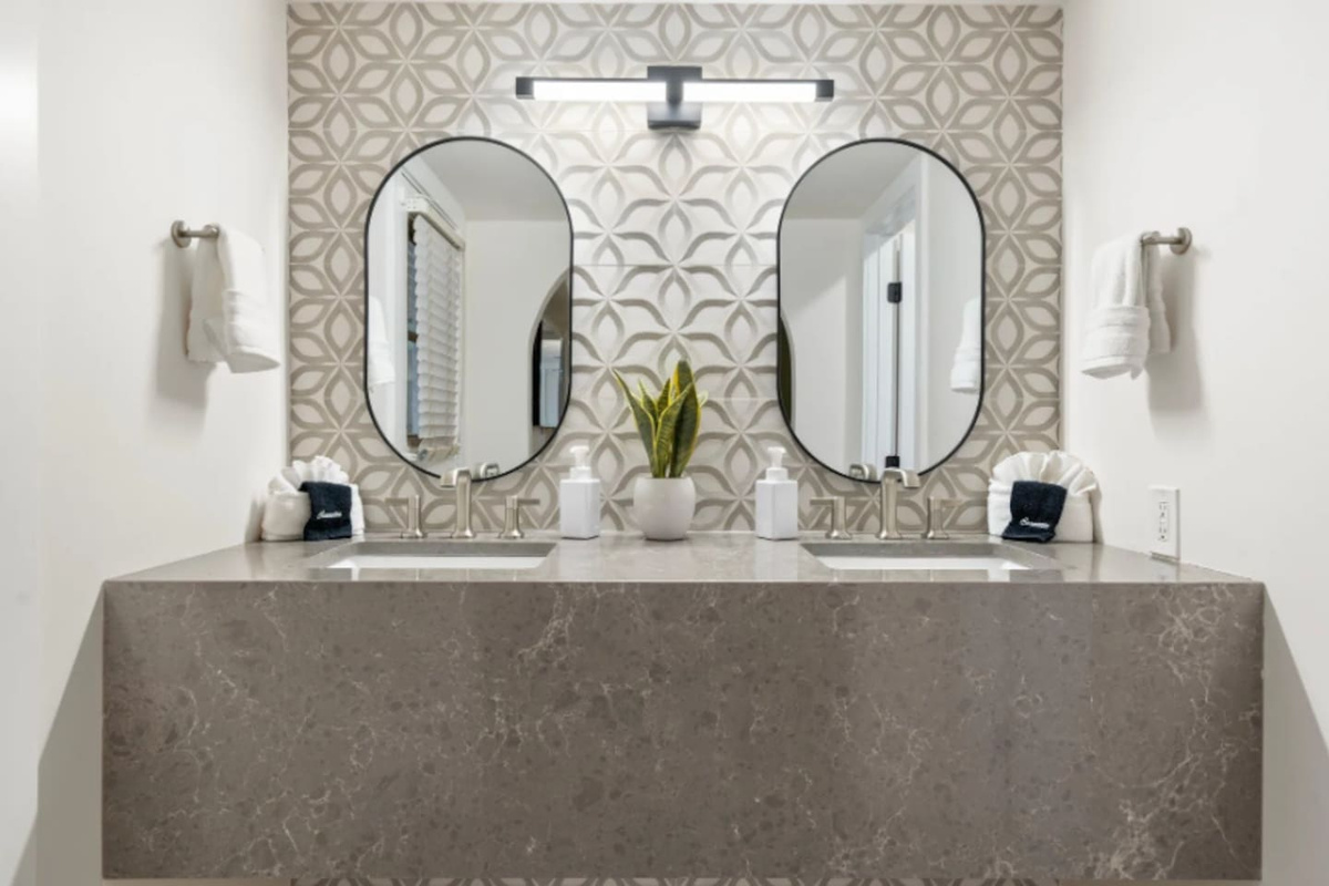 Two oval mirrors and a floating stone vanity make morning routines feel a little more indulgent. Fresh greenery and soft lighting add the finishing touch to this refined space.
