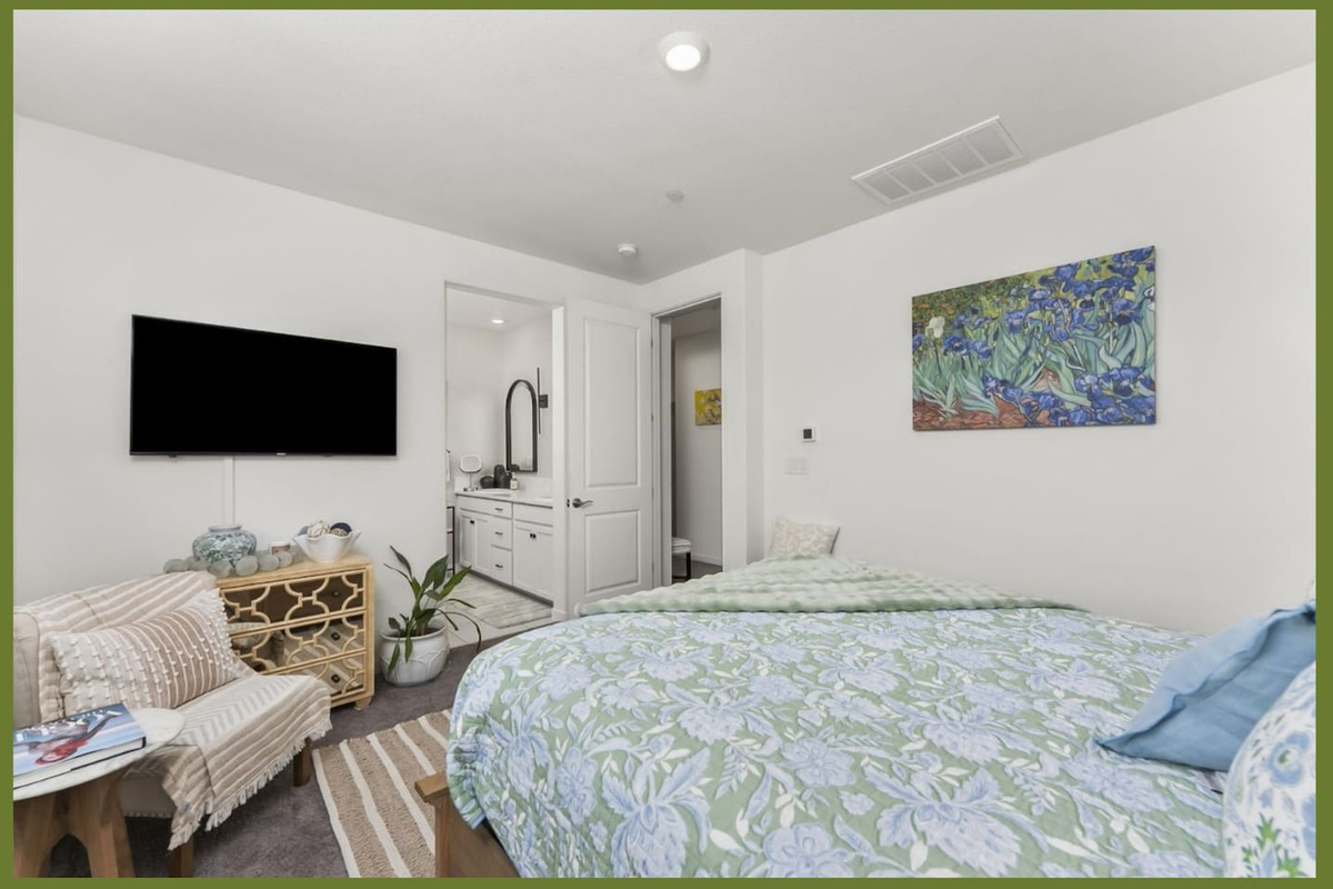 Bedroom with queen bed, mounted TV, accent chair, and relaxing aesthetics for a comfortable stay.