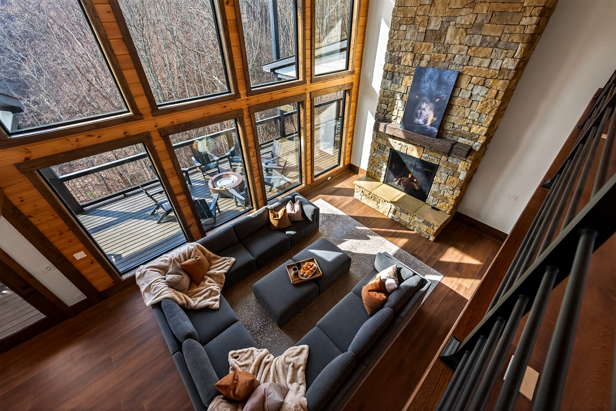 Gather beneath 30-foot vaulted ceilings surrounded by a wall of windows. Relax on the large sectional sofa beside the luxury fireplace with stunning floor-to-ceiling stone, creating a warm and unforgettable mountain lodge atmosphere.
