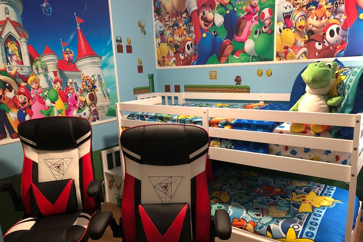 Twin/twin bunkbed room with Xbox and two gaming chairs with Mario decor.