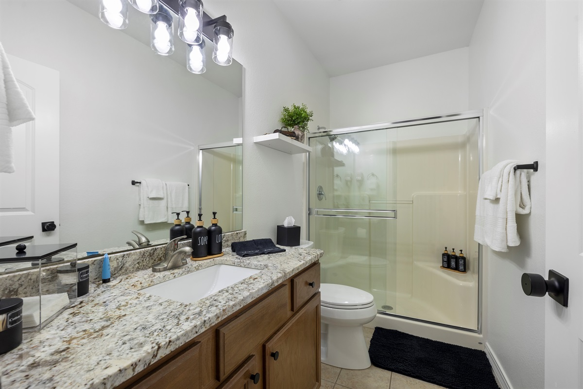 The shared third bathroom has large vanity top and walk in shower