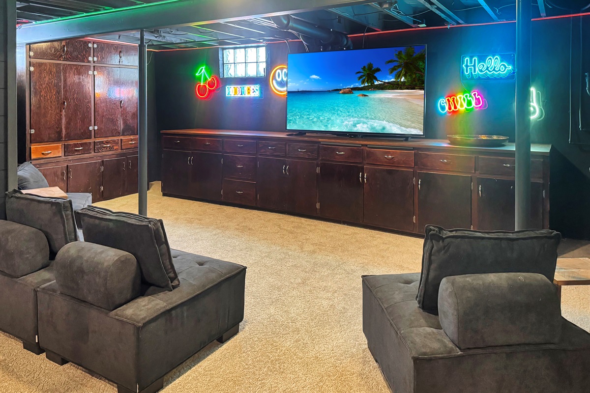 Big screen entertainment zone with cozy seating and neon glow.