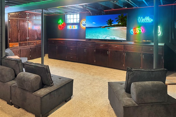 Big screen entertainment zone with cozy seating and neon glow.