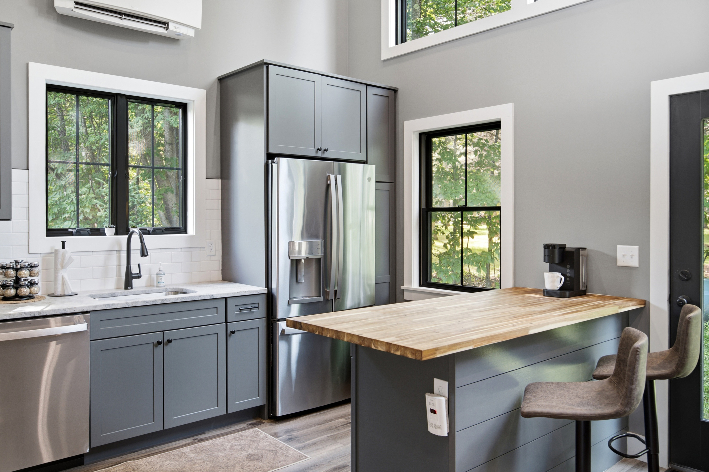 Bright windows bring the surrounding greenery into this stylish and functional kitchen.