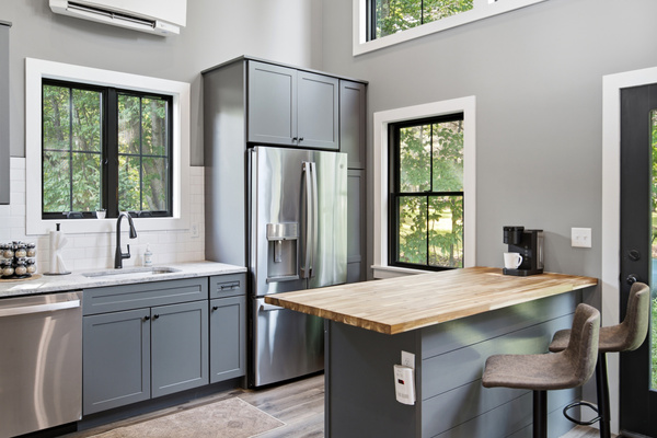 Bright windows bring the surrounding greenery into this stylish and functional kitchen.