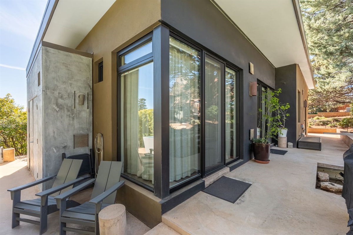 Modern mid-century exterior with floor-to-ceiling glass, private patio seating, and serene surroundings.
