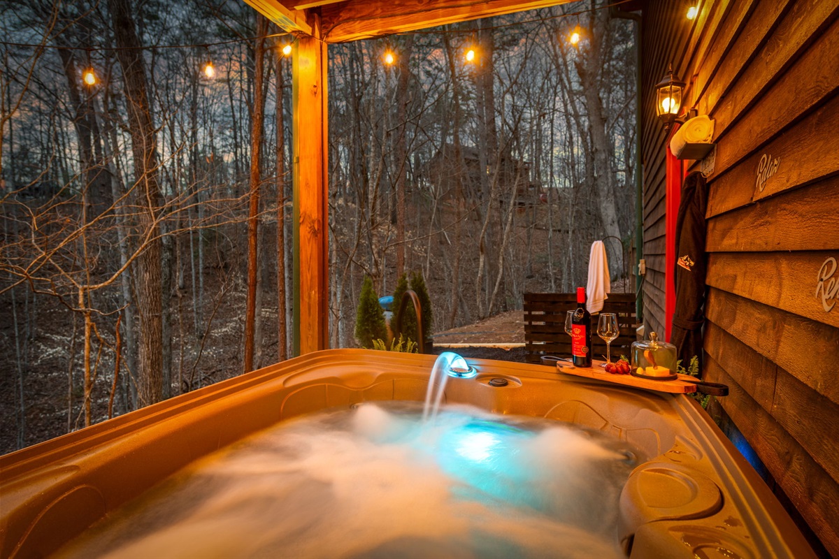 The hot tub glows invitingly under soft string lights, creating a warm and relaxing ambiance.
