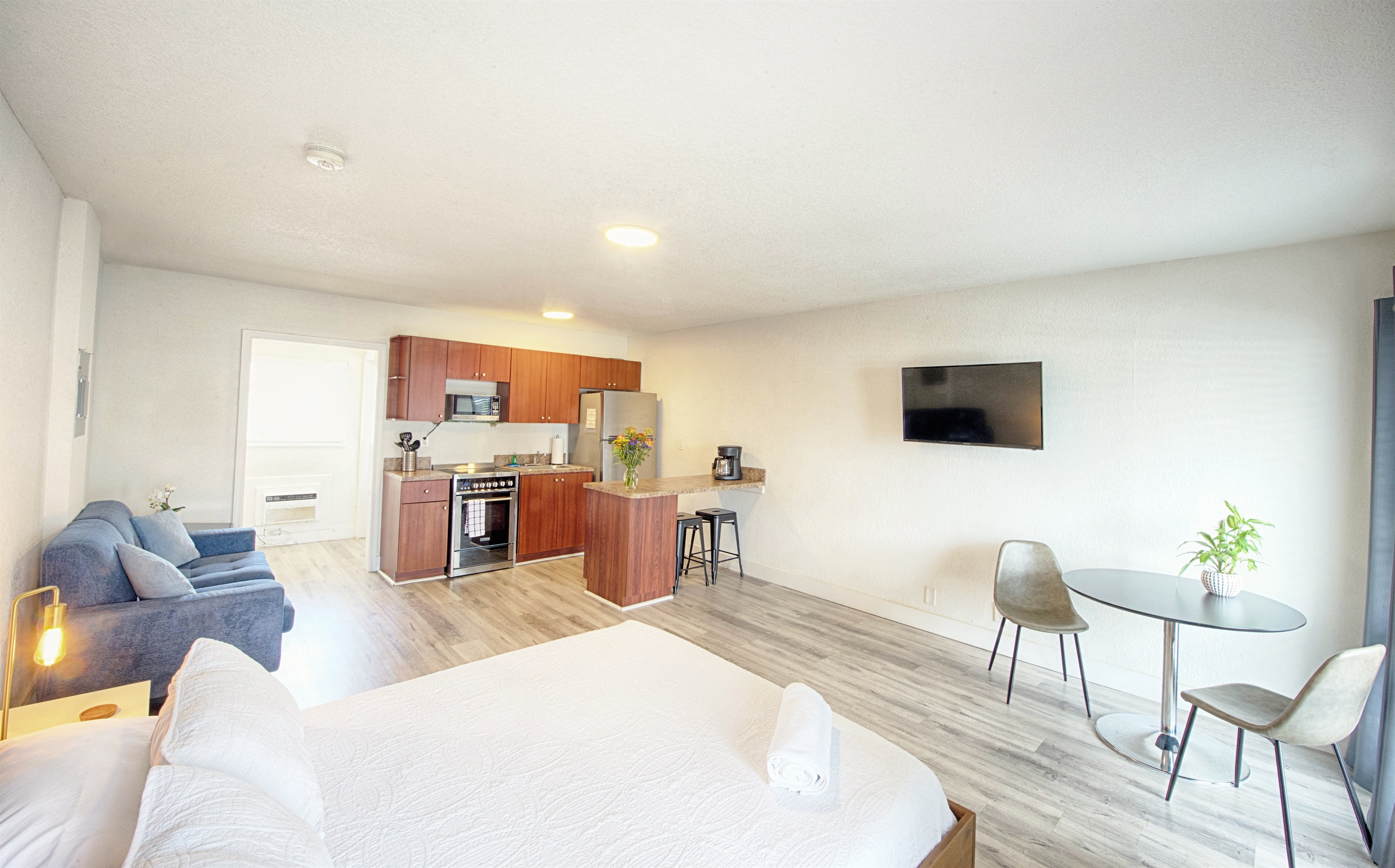 Welcome to your open concept studio apartment! View of bathroom entry, kitchen and dining table.