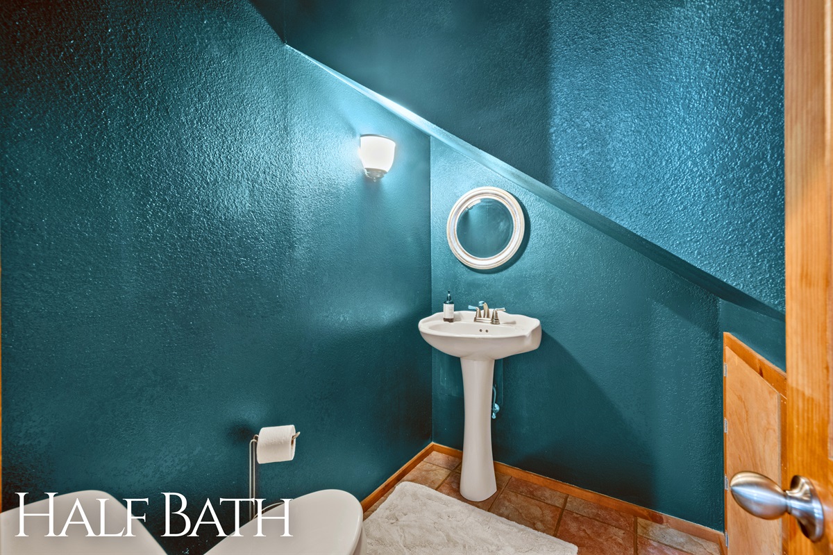 Convenient powder room with bright accent wall and pedestal sink.
