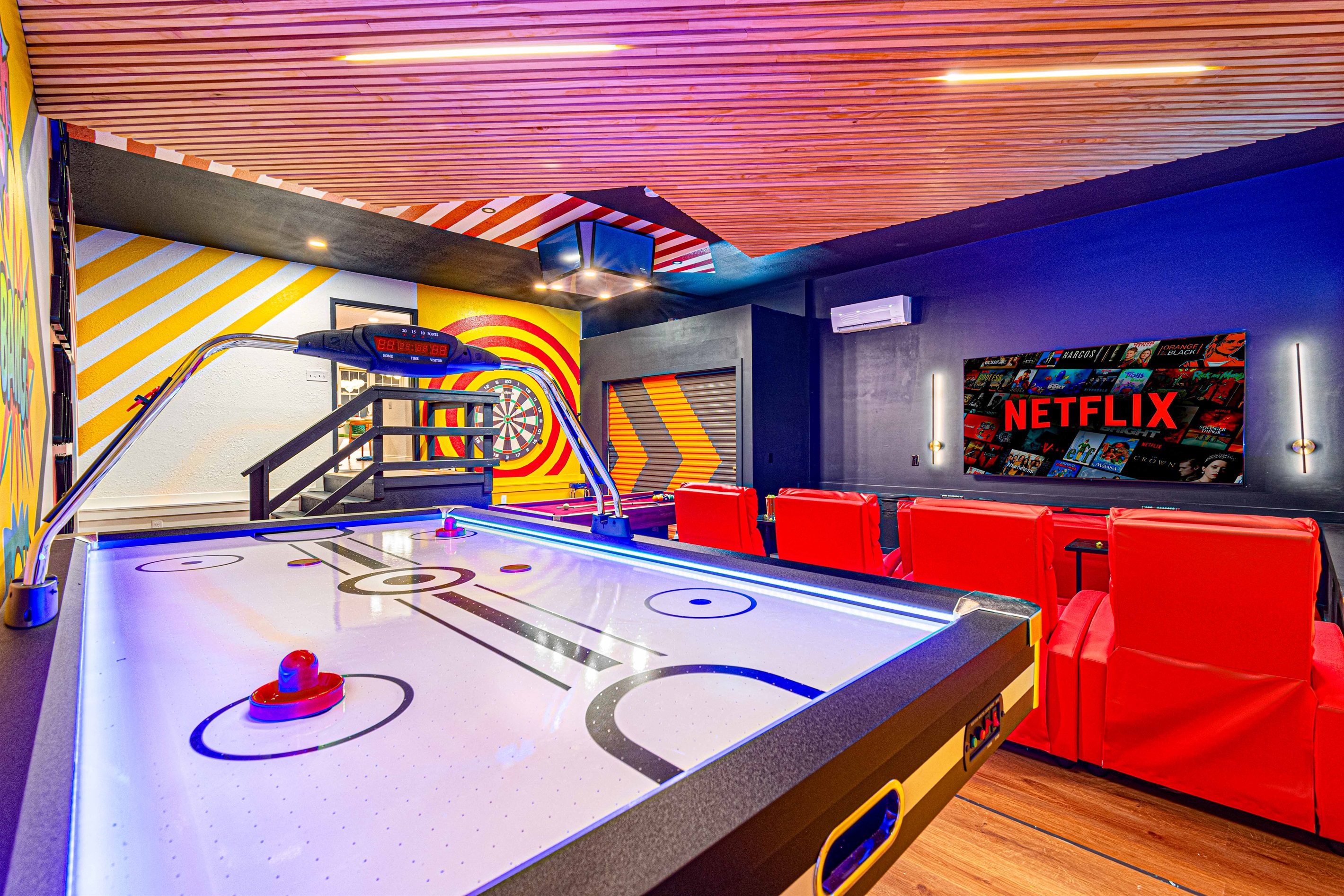 Challenge your friends to a game of air hockey or enjoy a movie from the comfy red recliners in this vibrant and exciting entertainment room.