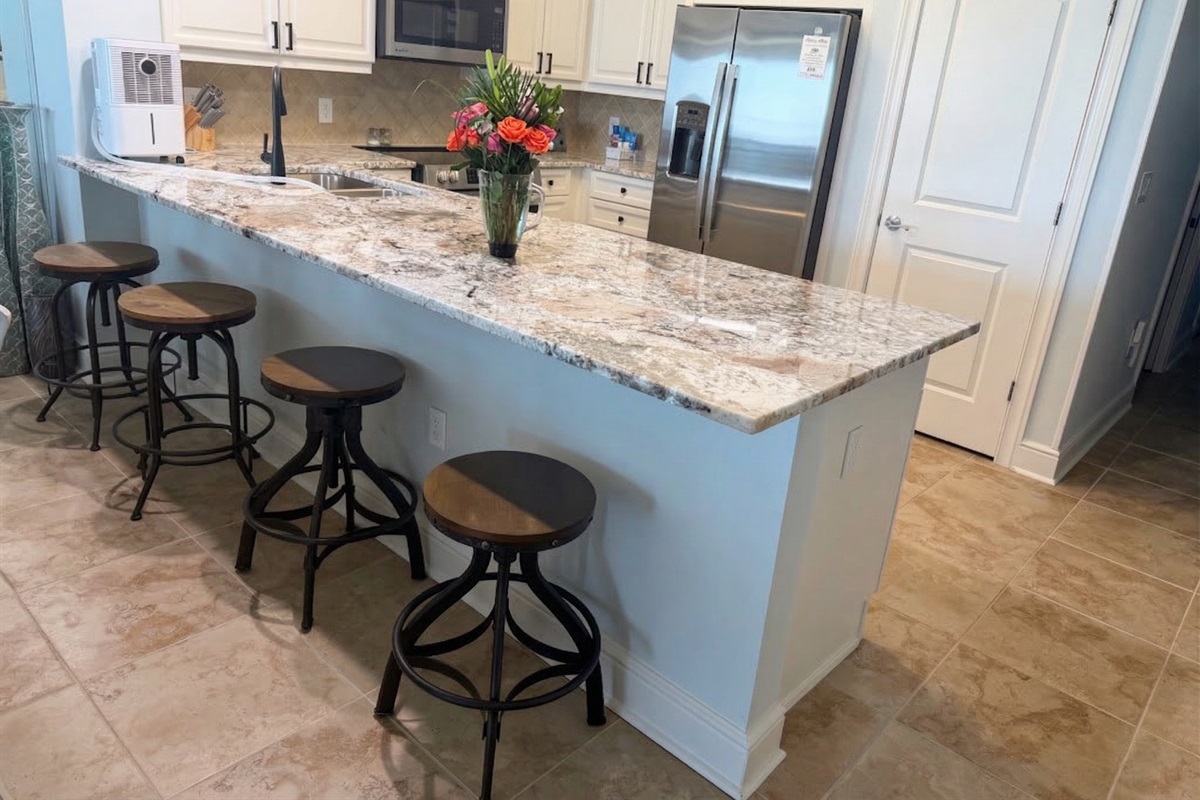 Spacious kitchen with granite countertops, stainless appliances, and bar seating—perfect for coffee mornings or family meals together.