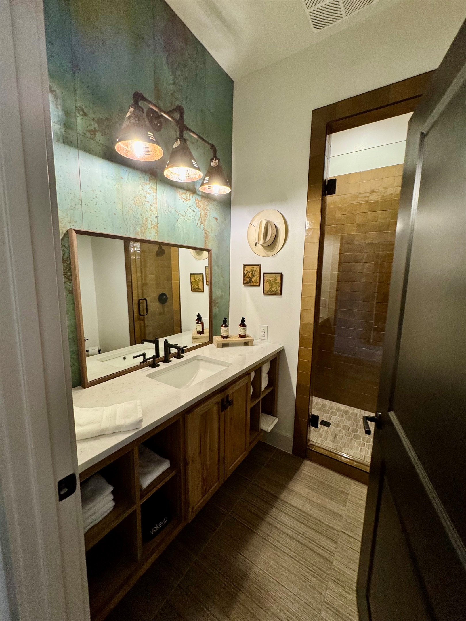 Private en-suite bathroom at the Corral Suite — a designer vanity, framed art, and modern Western finishes throughout.
