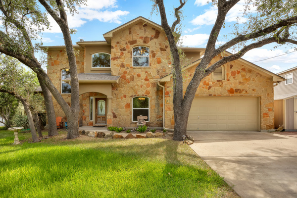 Stone lake house shaded by live oaks