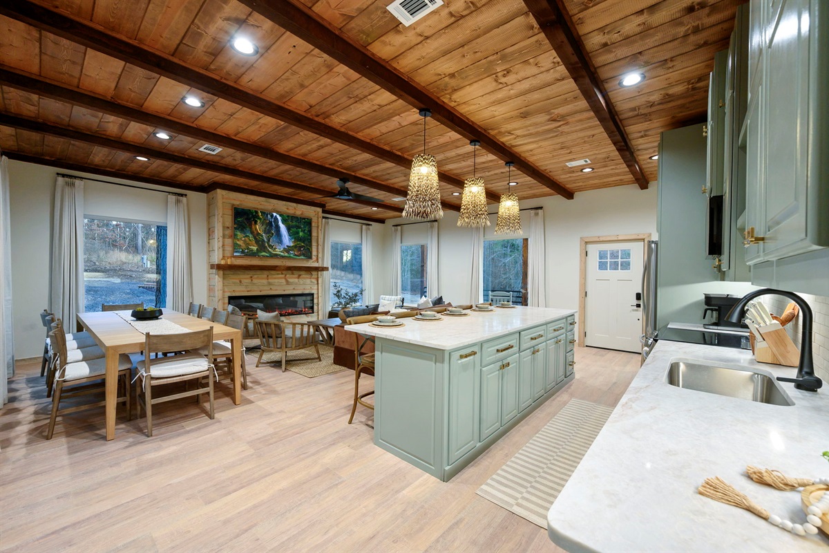 Bright, designer open-concept kitchen & living space with warm wood ceilings &mdash; perfect for gathering.