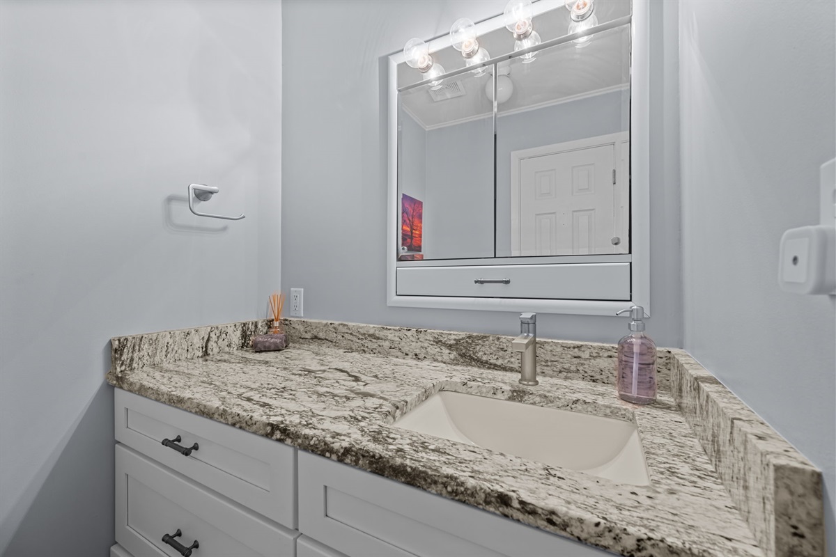 Main floor bathroom featuring a granite vanity and bright, clean finishes
