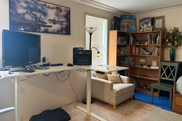 Work area with standing desk, TV serves as extra monitor with docking station. Book-nook and reading chair.