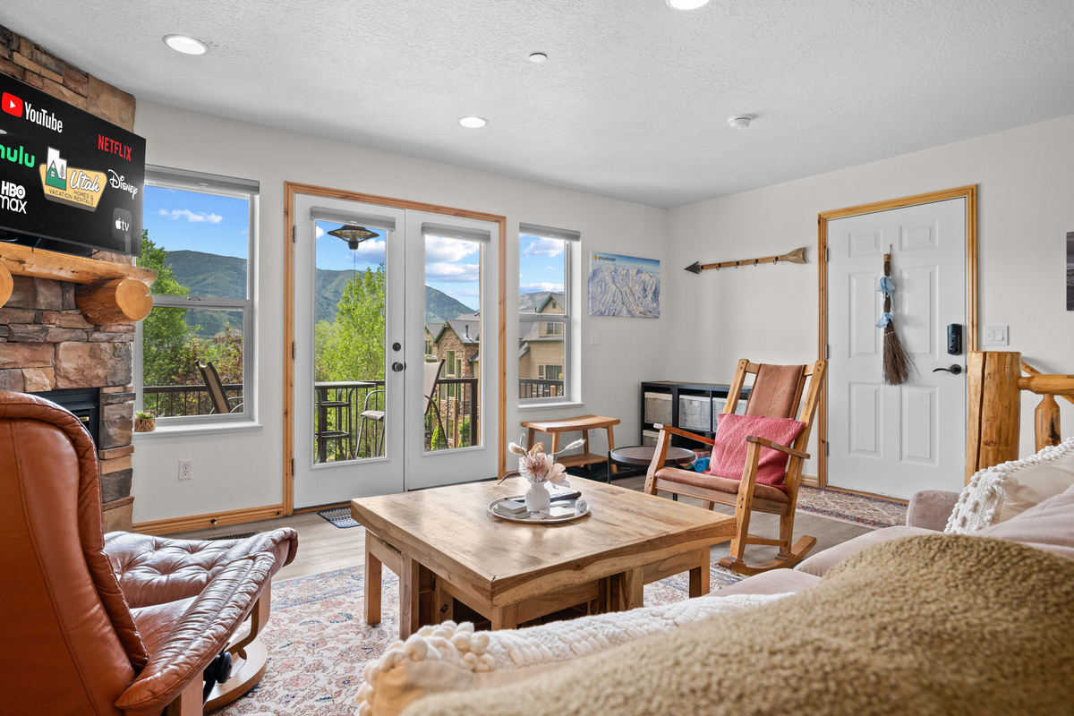 This spacious living area features two rocking chairs, a sleeper sofa, and seamless access to the outside balcony.