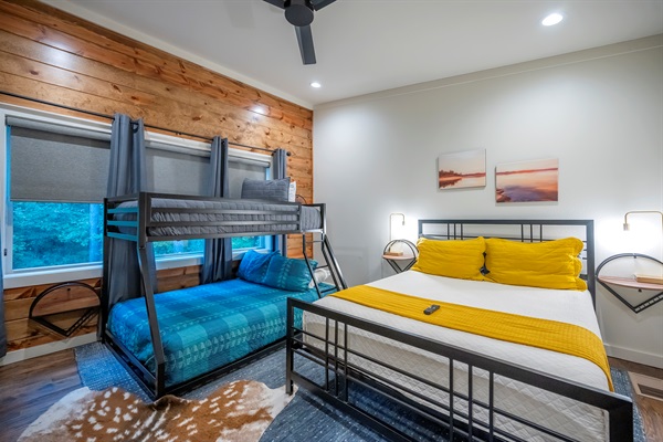 Bright and inviting guest room with a queen bed and twin-over-full bunk — perfect for families or friends who love comfort, style, and forest views