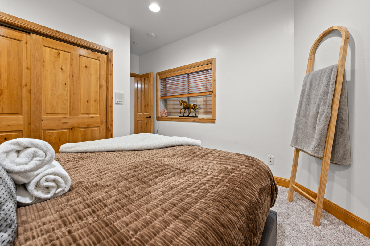 Peaceful guest bedroom with warm wood accents, comfortable bedding, and convenient storage.