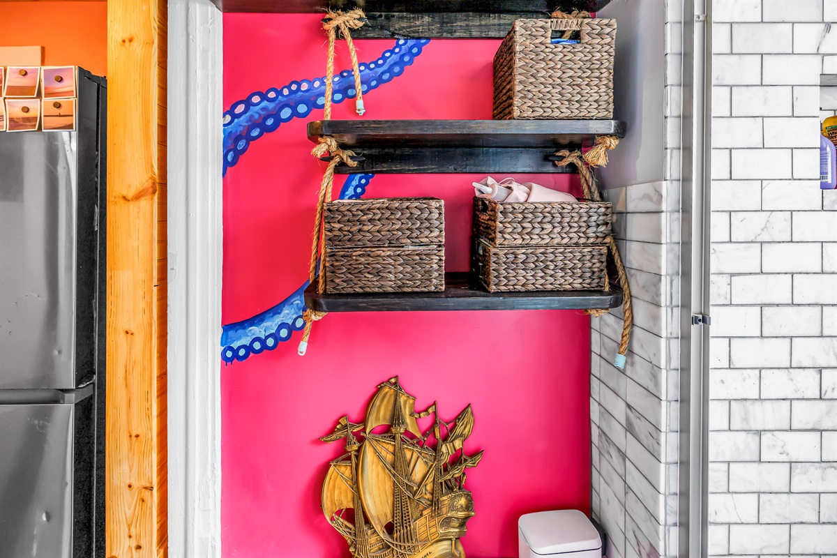 Decorative bathroom storage with open shelving, woven baskets, colorful accent wall, and bright tile details.