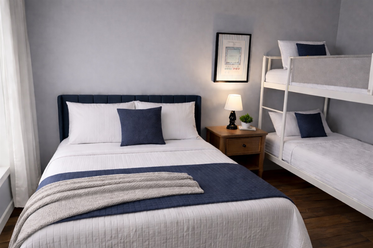 Thoughtfully designed bedroom featuring a plush queen bed and cozy twin bunk beds—designed for comfort and relaxation. Sleeps 4 people.