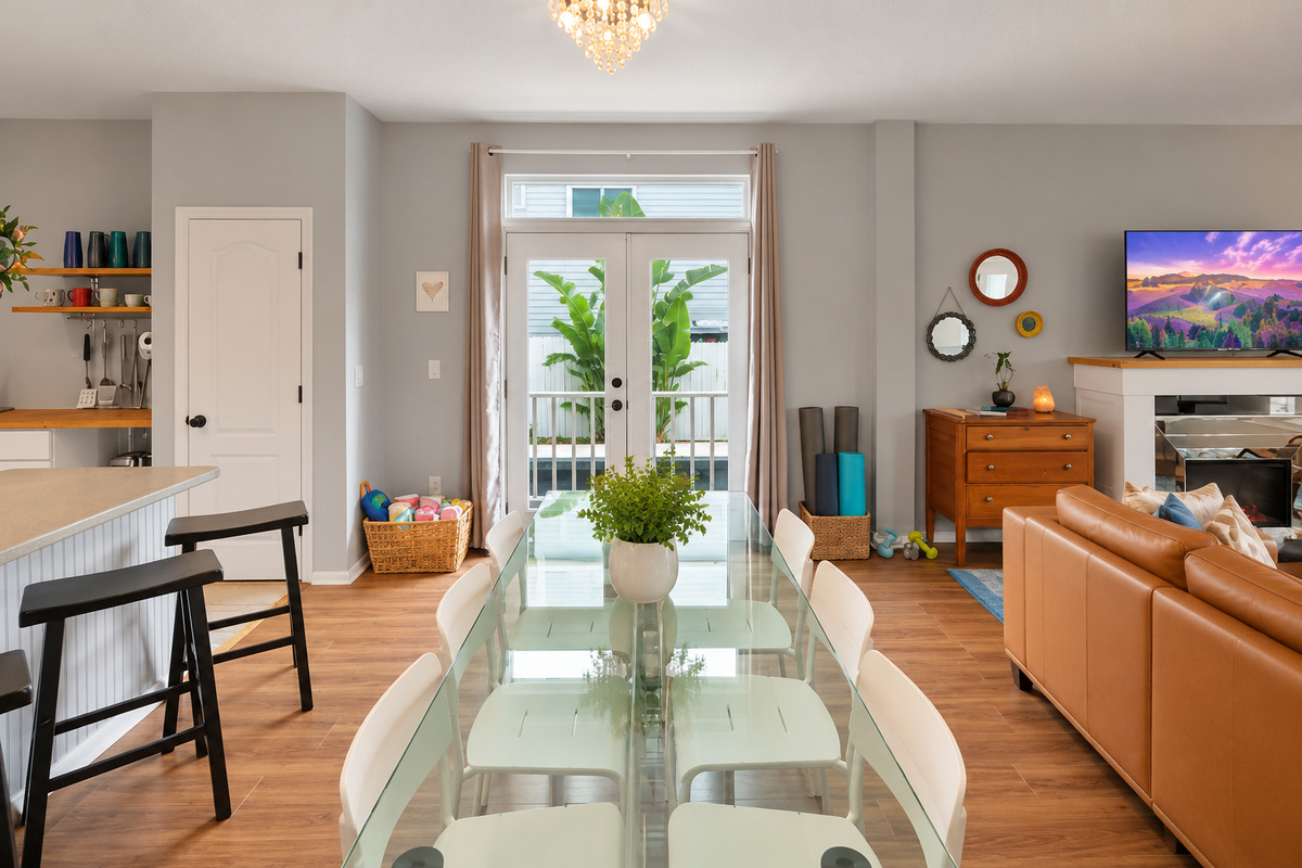 Glass dining table by the French doors, with a basket of sand toys ready to grab, so breakfast rolls into beach time.