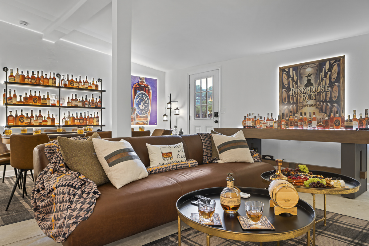 Two leather sofas, a full bourbon display wall, and the Rickhouse Run sign set the tone for a game room designed to impress.
