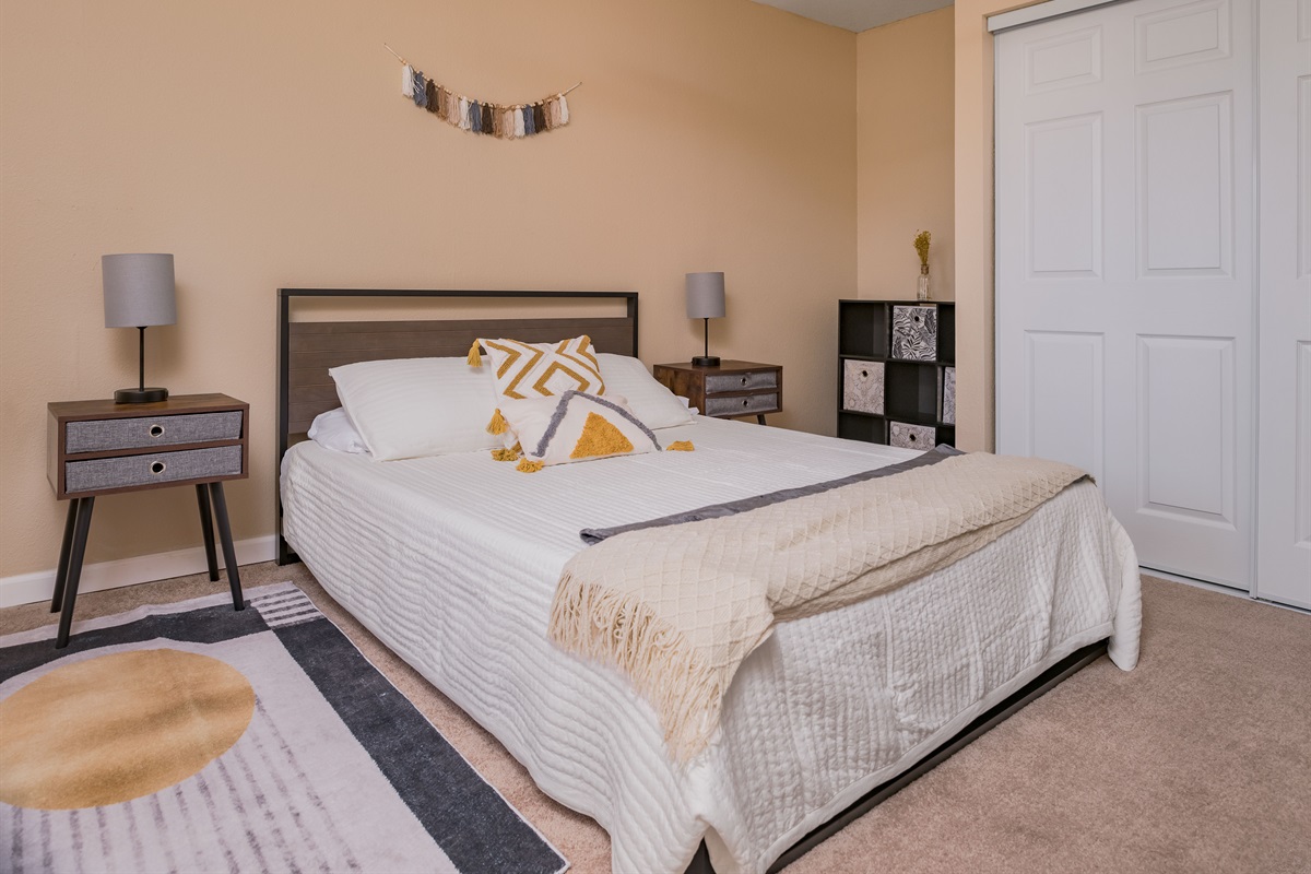 This stylish bedroom blends modern decor with warm, earthy tones, offering a restful space complete with cozy textures and thoughtful touches.