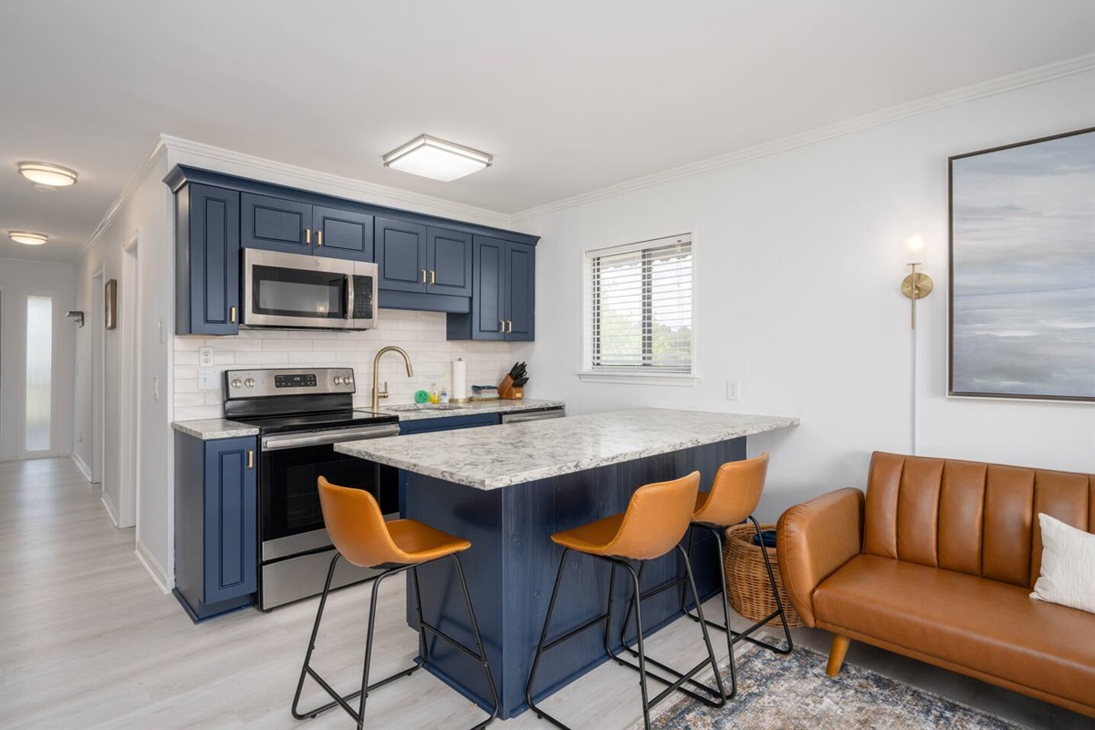 Updated kitchen featuring quartz countertops, new cabinets, new appliances, and island that seats three. A well equipped kitchen with everything you need for cooking during your stay!