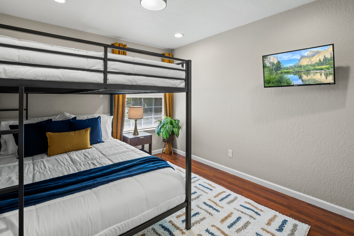Versatile bunk room featuring a twin-over-full bed, comfortable bedding, and a wall-mounted TV, perfect for kids, teens, or additional guests.