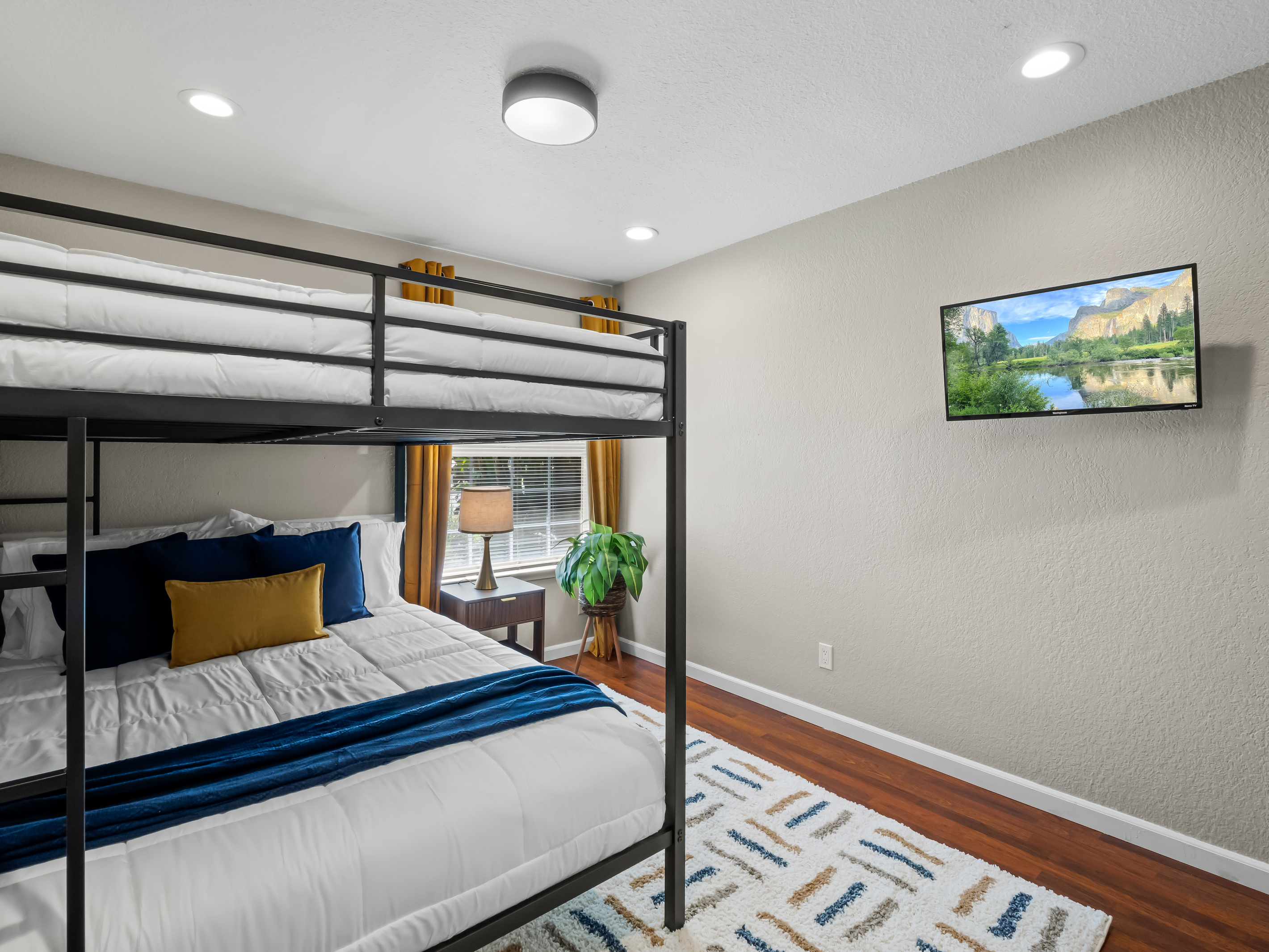 Versatile bunk room featuring a twin-over-full bed, comfortable bedding, and a wall-mounted TV, perfect for kids, teens, or additional guests.
