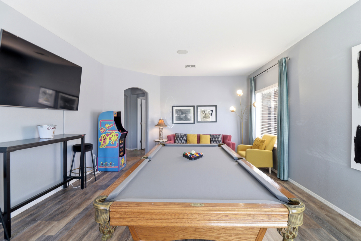 Game room with a pool table, arcade game, TV, and space to hang out.
