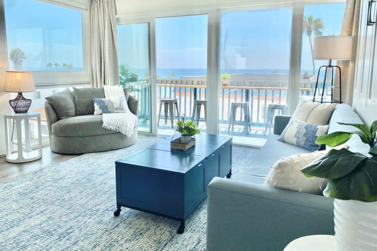 The living room has lots of comfortable seating, views and natural light pouring in from the balcony.