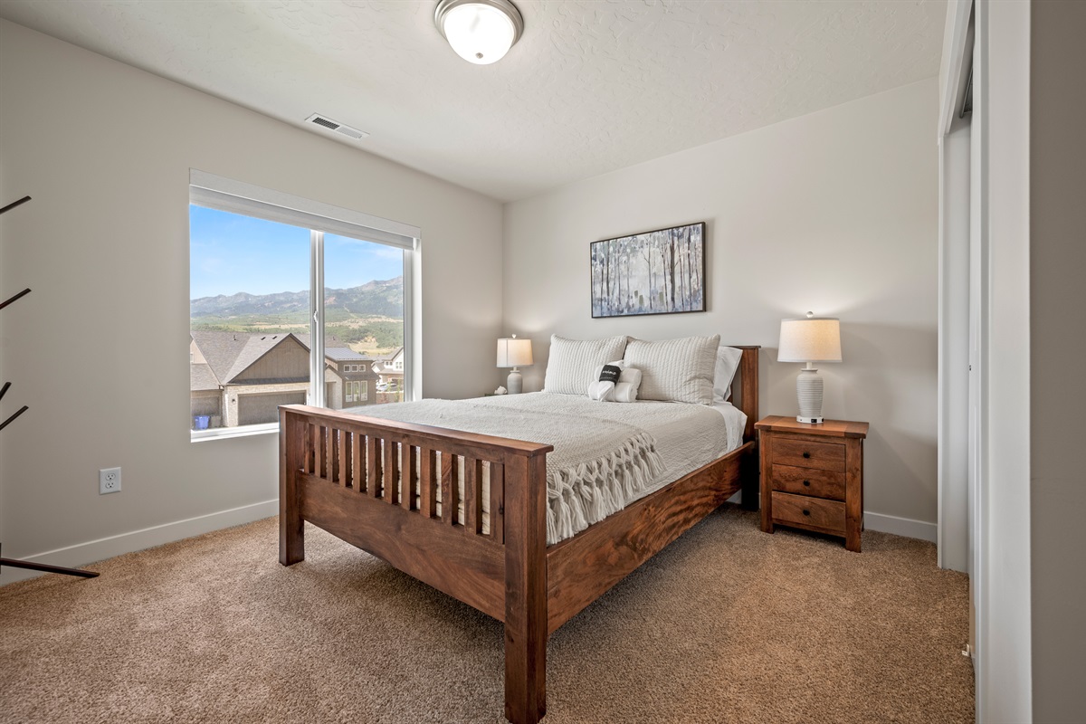 Elegant and inviting—this upstairs queen bedroom offers stunning mountain views, luxury linens, and warm wood furnishings for a restful retreat.