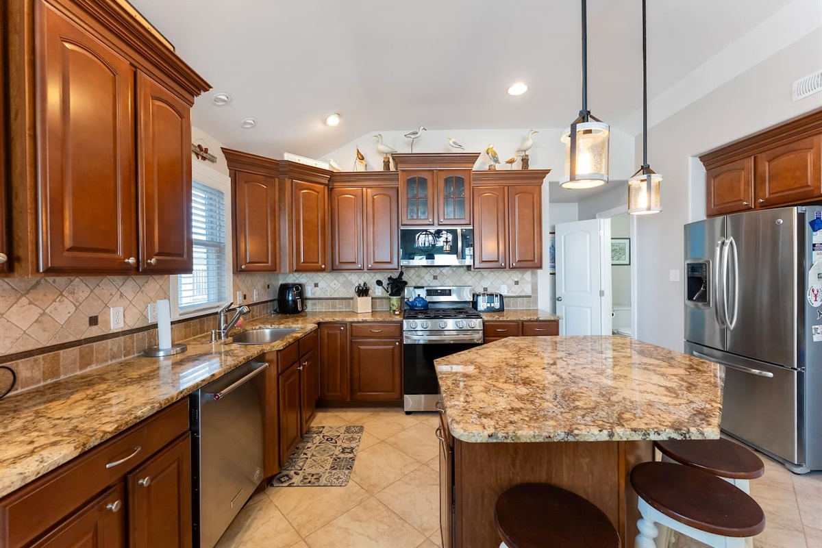 Full kitchen with stainless steel appliances, large island for additional seating, ample prep space and separate beverage refrigerator. 