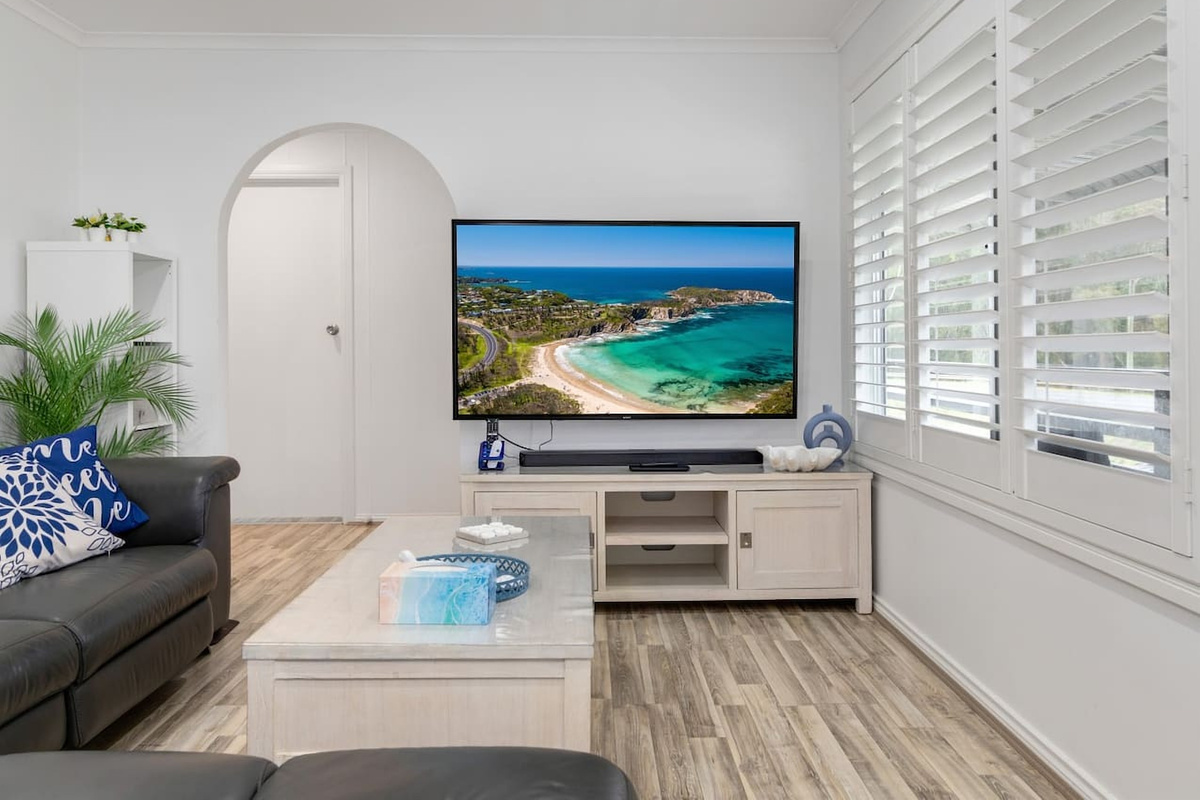 The upstairs living area at Skye’s Beach House Malua Bay keeps the main level open and relaxed, with natural light across the lounge zone.