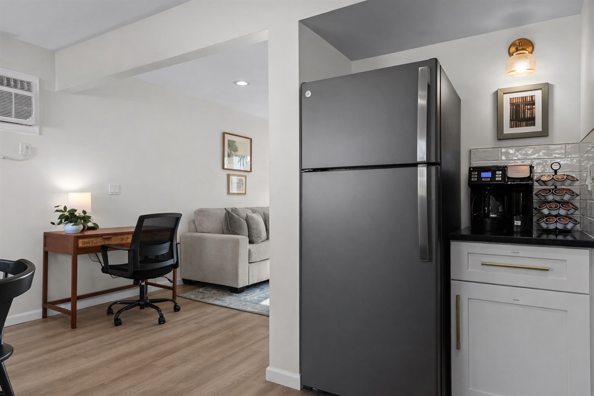 Thoughtfully designed kitchen corner with coffee station and modern appliances, flowing seamlessly into the living area and dedicated workspace.