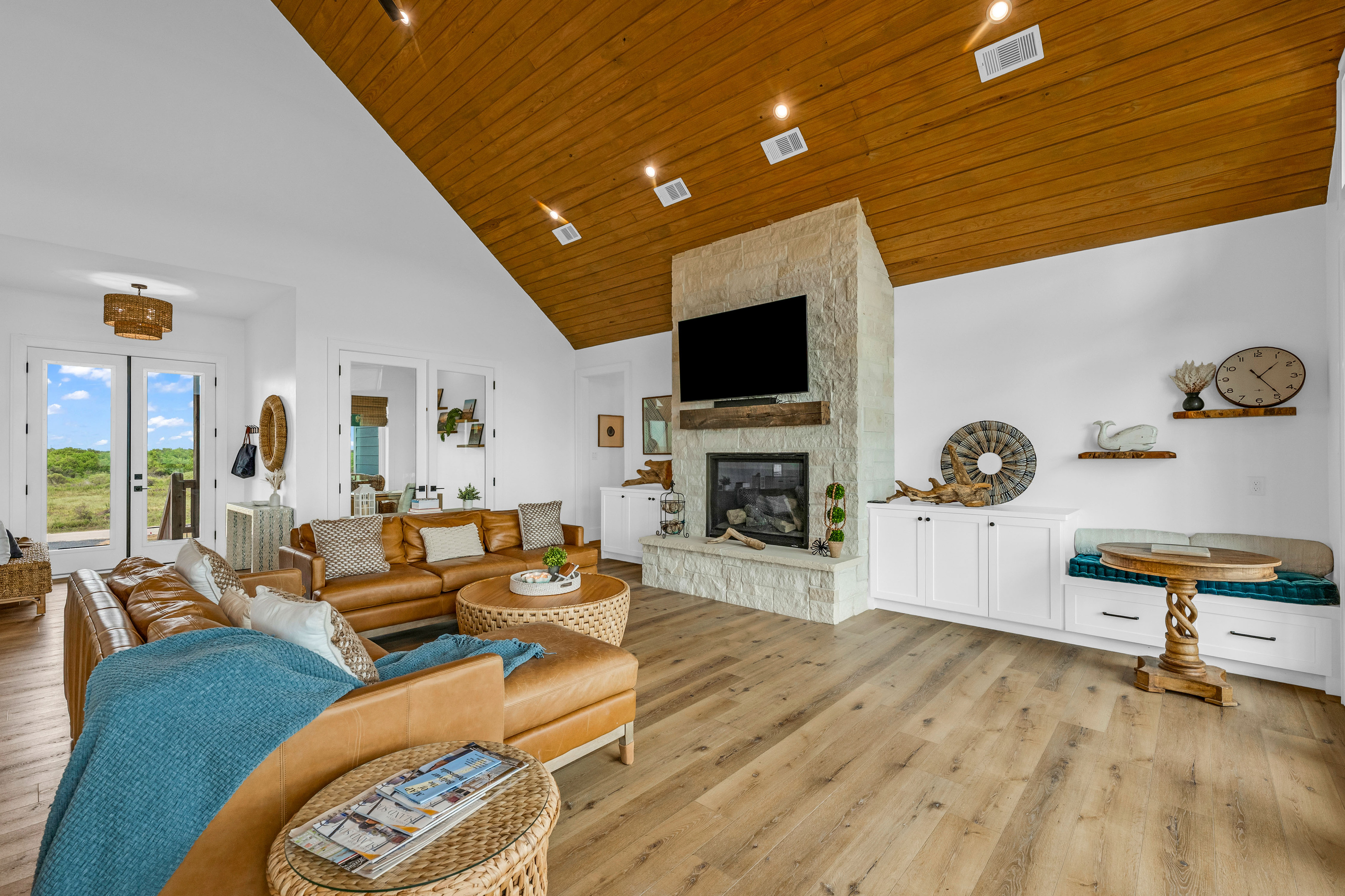 Cair Paravel: Cognac leather sofas and a woven jute coffee table anchor the great room, with the kitchen and a sunny window nook just steps away.