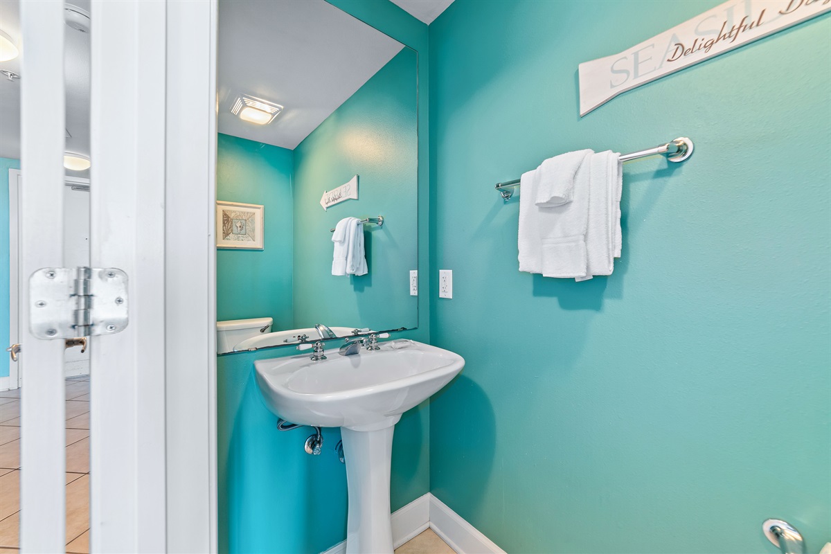 A convenient and charming half bath, located in the hallway for easy access. Its vibrant coastal theme and stylish decor make a delightful and practical addition for all your guests.