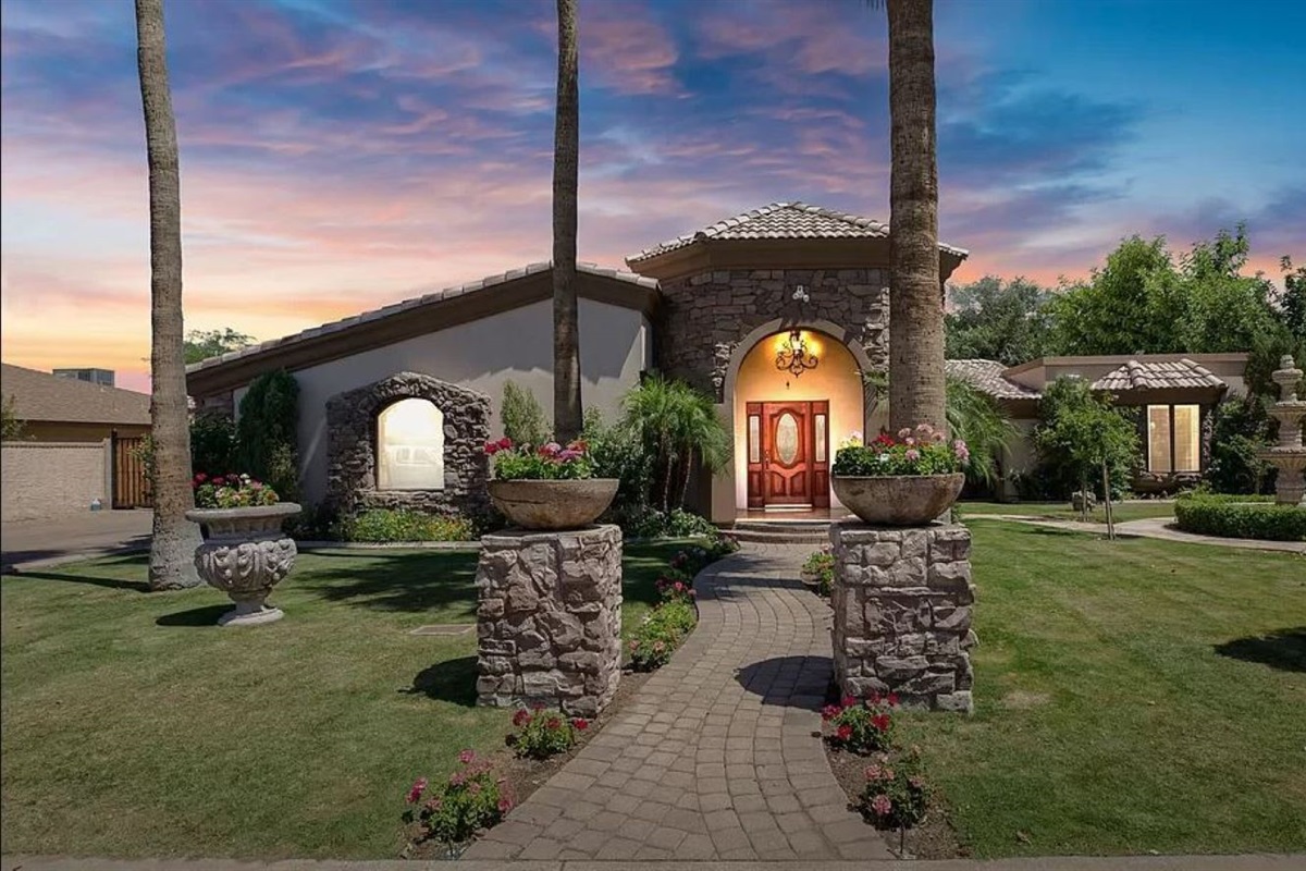 Step into your private oasis, a stone-accented haven surrounded by lush gardens, glowing sunsets, and a grand entrance that warmly welcomes you home.