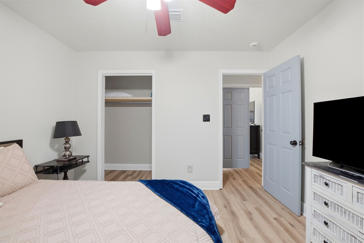 This cozy bedroom offers a comfortable bed, flat-screen TV, and convenient closet space for your stay. The simple layout and neutral tones create a relaxing environment, perfect for unwinding after a day of exploring the area.
