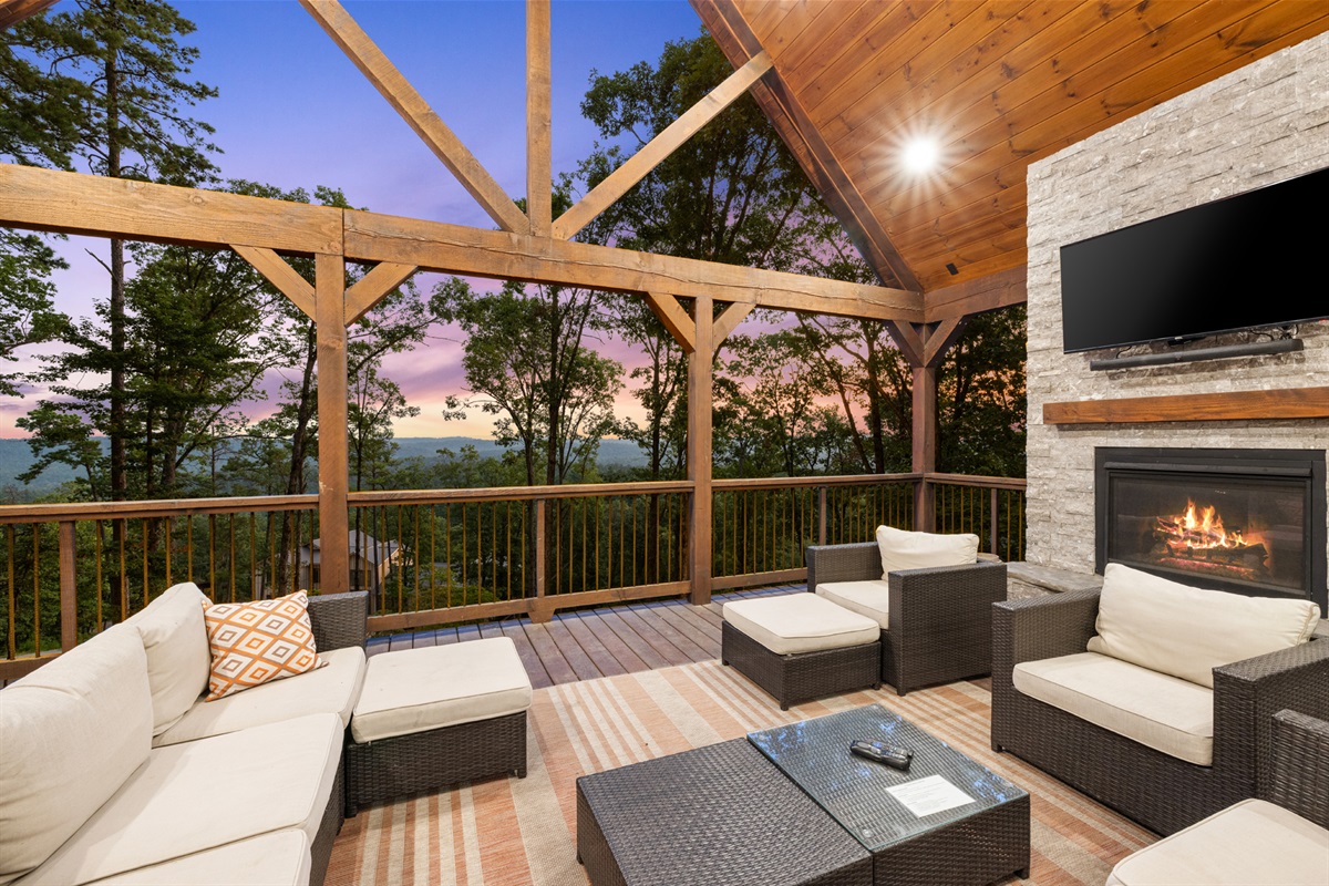 Covered outdoor lounge with fireplace, comfortable seating, and mountain views