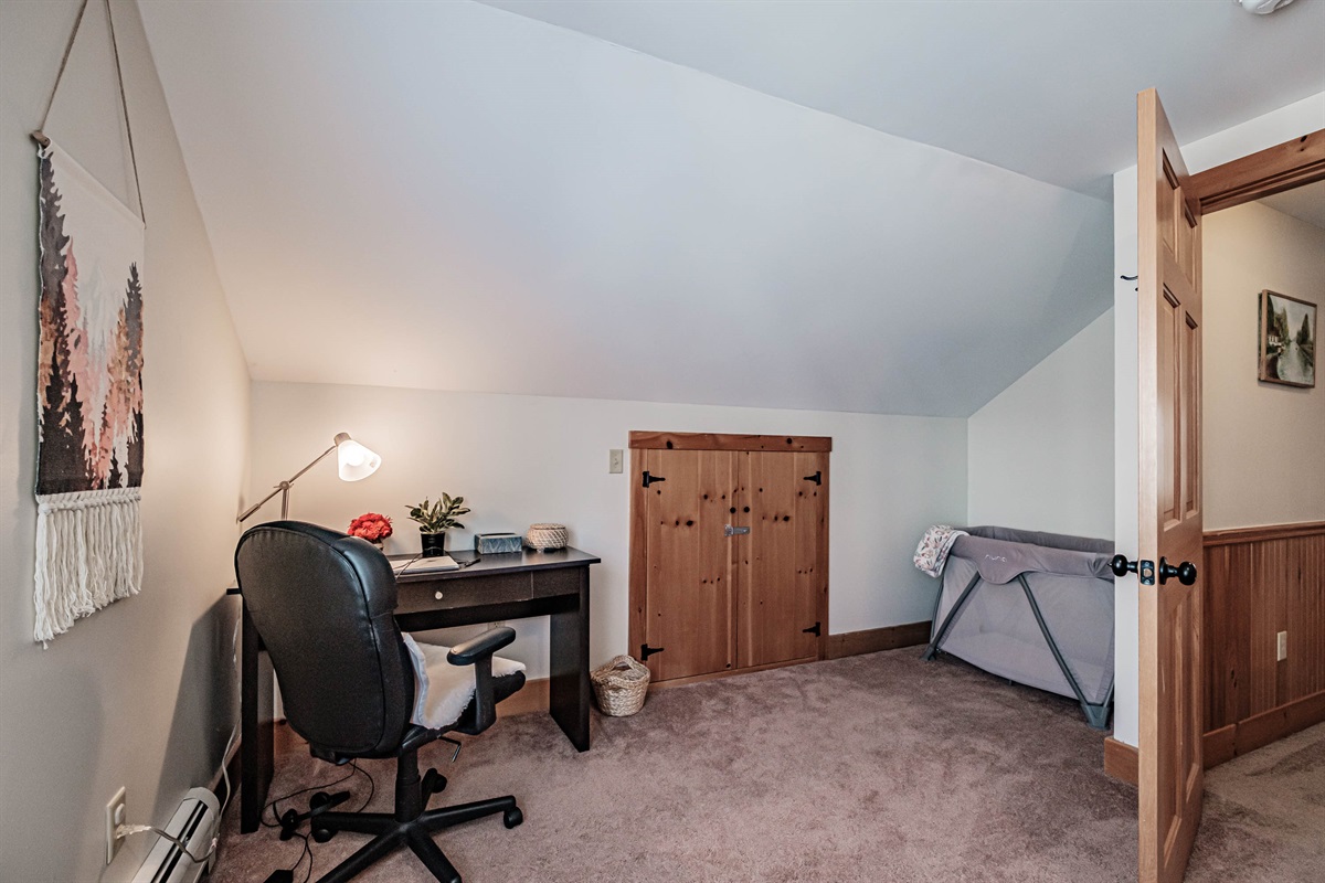 Second-floor queen bedroom with a comfortable queen bed, cozy crib, and convenient workspace.