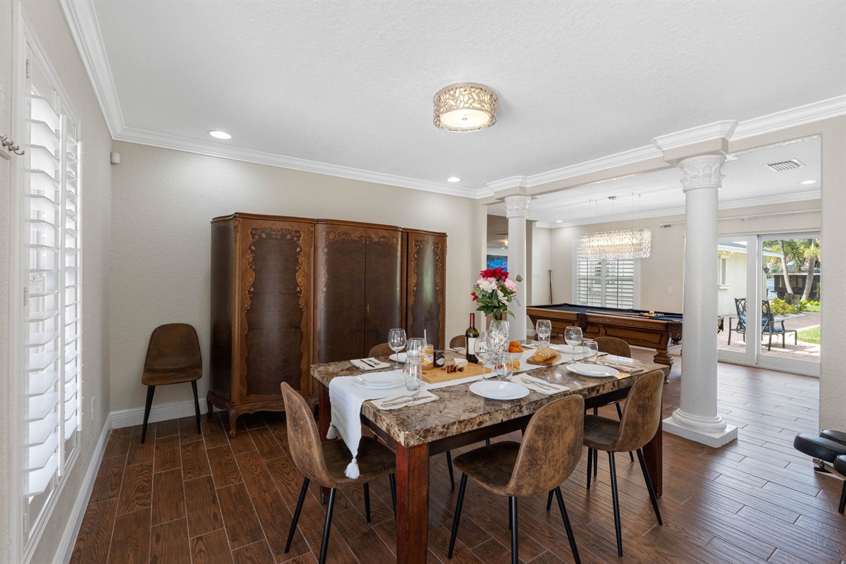 Natural light pours through plantation shutters, illuminating the beautifully set table and creating a welcoming atmosphere.