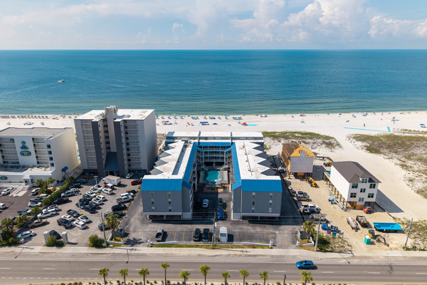 Aerial view of the building, parking, and beach access just steps away